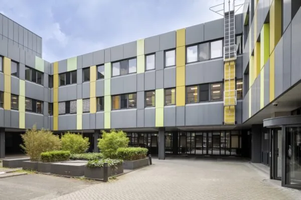 Binnenplein van een modern kantoorgebouw aan de Van Boshuizenstraat met grijsgevels en verticale gele en groene accenten.